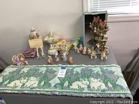 Top down photo of table with Easter decor items including bunny figurines, Bunny Tree House, and table runner