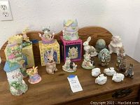 Full view of Easter bunny and house decor items collected on a wooden table including various figurines and boxed pieces.