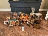 Wide view of all fall decor items arranged in front of a large storage bin on wood floor.