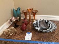 Group photo showing six vases of varied colors and shapes, and three decorative glass bowls with marbled patterns on a wooden floor.