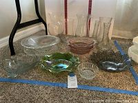 Wide view showing the full assortment of glass serving pieces including bowls and vases of various sizes and colors.