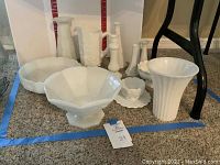 Milk glass assortment showing bowls, scalloped edged pieces, and pedestal bowls grouped together on carpet.