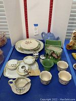 Overview of the Nippon hand painted vanity set including bowls and cups, green flamingo vase, blue teapot, and other ceramic items