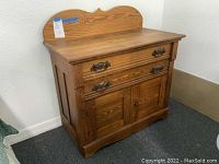 Full view of the oak cabinet with back panel, showing two drawers and double-door compartment below.
