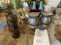 Photo showing a pair of silverplate salt and pepper shakers, wooden grinders, and the ceramic couple novelty shakers in the background.