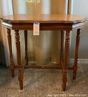 Front view of wooden side table showing detailed legs and shaped tabletop edge