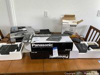 Two Panasonic microcassette transcriber tape recorders in original boxes, visible on table along with Sanyo tape recorder box and Brother printer.
