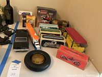 Photo showing various vintage collectible Avon bottles in original boxes along with boxed Ertl die-cast collectible cars and trucks, a CAT tire bank, and a black vintage toy car.