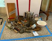 Photo showing the full assortment of vintage kitchen utensils including coffee pot, kettle, mandoline slicer, spoons, ladles, and other metal tools with some rust and wear.
