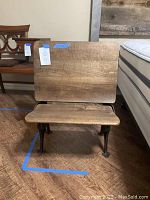 Front view of vintage wooden school chair with folding seat and wooden backrest and desk surface, showing worn wood grain and cast iron frame.