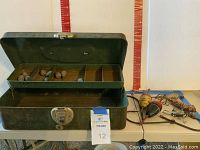 Open vintage metal tackle box showing top tray with compartments containing several metal weights.