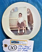 Top view of the china plate showing the full vignette artwork centered and the gold rim.