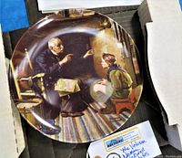 Front view of the collectible plate depicting an elderly man and a boy, inside a partial view of the original box.