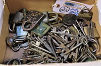 Box lot showing an assortment of skeleton keys, padlocks, and a leather pouch with visible metal patina and wear.