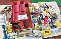 Overview of the full lot showing a variety of hand tools and hardware, including the red tool organizer, hammers, small boxes of nails, tape, and assorted items.