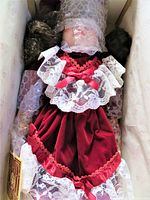 Close-up of Alexandra doll wrapped in bubble wrap inside original box, showing detailed lace and velvet dress