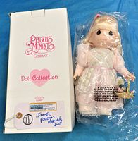 Photo showing the Precious Moments doll in original packaging and box labeled 'Doll Collection' with model name and number.