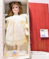 Doll in original box with white lace trimmed dress, auburn hair, certificate partially visible.