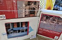 Photo showing three boxed sets of outdoor Christmas light decorations including standing coil reindeer and lighted deer and sleigh figures.