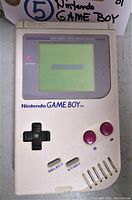 Front view of the vintage 1989 Nintendo Game Boy showing the screen with battery indicator lit and control buttons below it.