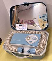 Open blue vintage Sears portable hair dryer inside its matching mirror case, with hose coiled around the dryer unit.