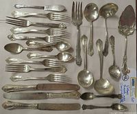 Overview of 23-piece vintage silver plated flatware and serving set showing forks, knives, spoons, and specialty utensils in ornate vintage pattern with moderate tarnishing.