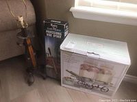 Lot items displayed near couch including boxed wine opener, metal decorative lamp, and boxed beverage dispenser set showing glass jars and metal carrier.