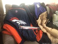 Photo showing the Denver Broncos navy and orange jacket with large team logo on the back and NFL logo on the collar, along with one fleece and another jacket.