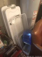 Photo showing two large white plastic storage bins stacked against a concrete wall with lids visible.