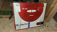 Box packaging showing front view of Roomba Red robotic vacuum with iRobot branding and seller's price tag.