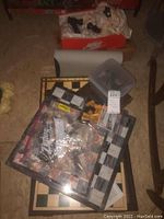 Boxes on floor with chess boards, plastic container with chess pieces, and bags with pieces inside a Nike shoe box.