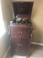 Victrola wooden cabinet with hinged top open showing turntable and side crank