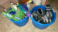 Two blue bins, one filled with vintage style Super Soaker water guns of multiple colors and models.