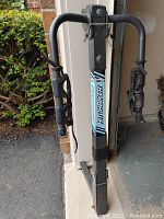 Front view of the Bell Hitchbiker 2-bike hitch rack showing the black metal frame, padded arms with Velcro straps, and the central label.