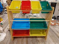 Front view of toy organizer showing 8 colorful plastic bins on 4 shelves with wooden rungs, on laminate wood frame