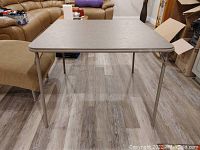 Card table at an angle showing metal legs and plastic tabletop surface