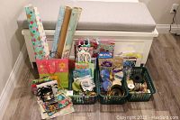 Full lot showing all rolls of wrapping paper, gift bags, tissue paper, bows, ribbons in green plastic bins in front of a bench.