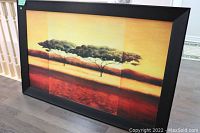 Framed print showing a wide landscape with an acacia tree silhouette and warm-toned gradient sky and land.