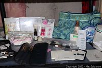 Various makeup brushes, cosmetic sponges, travel bags, jars, and skincare samples displayed on table