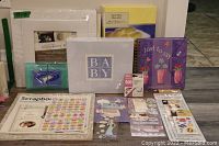 Photo shows an assortment of scrapbooking albums, stickers, kits, and paper arranged on a floor.