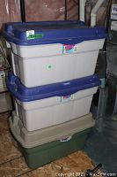 Three Rubbermaid RoughTote plastic storage bins stacked on top of each other, two with blue lids and one with a green lid, showing condition and size.