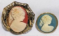 Two cameo brooches together, showing profile details and overall size difference.