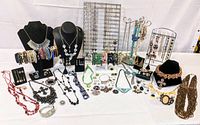 Full display of necklaces on busts, bracelets on stands, earrings, brooches, and charms.