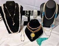 Wide view showing entire lot of pearl and gemstone jewelry including necklaces and bracelets displayed on stands