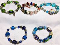 Five colorful glass bead bracelets arranged on a white background showing a range of themes and colors