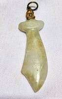 Jadeite saber sword pendant front view showing smooth carving and metal loop with floral design