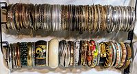 Two rods displaying a large number of assorted bangle bracelets in various designs and colors.