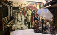 Two canvas art prints leaning against a wall in a dimly lit room, showing city scenes with people walking and umbrellas, colors mainly muted with some bright elements.