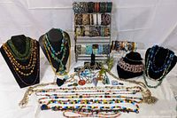 Overall lot arranged on display busts and multi-tier bracelet stand showing necklaces, bracelets, pendants and scarf