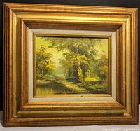Framed oil painting of wooded landscape with trees and stream, signed lower right by Irene Cafieri. Gold tone wide frame with layered molding.
